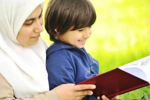 Mother Muslim and her son in the nature, reading together